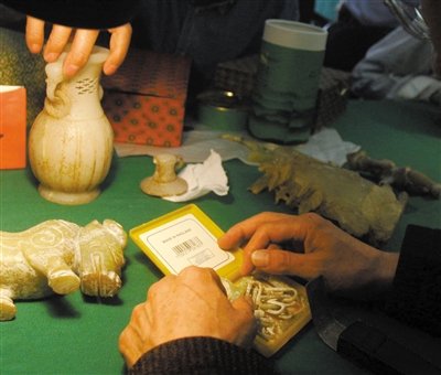 2009年,专家鉴宝活动现场,一名文物鉴定专家为市民鉴定玉器.